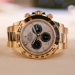 Gold Rolex Daytona wristwatch with bronze dial and three black subdials on a light surface.