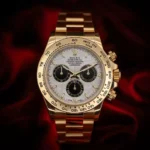 Gold Rolex Daytona wristwatch with white dial and black subdials, close-up shot.
