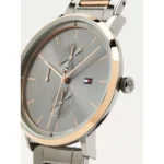 Close-up of a two-tone wristwatch with a silver band, rose-gold bezel, gray dial, and a small Tommy Hilfiger flag logo on the face.