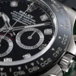 Close-up of a Rolex Daytona watch dial showing subdials, diamond markers, and numeric bezel with 'Rolex' branding.