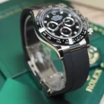 Close-up of a stainless steel Rolex chronograph with a black dial, diamond hour markers, and a black tachymeter bezel on a rubber strap
