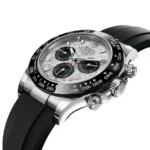 Close-up of a silver Rolex chronograph watch with a black tachymeter bezel and rubber strap, showing three sub-dials and a textured dial.