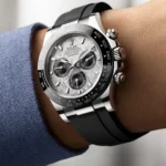 Close-up of a Rolex Oyster Perpetual Cosmograph Daytona on a wrist, featuring a textured silver dial, black bezel, and black rubber strap.