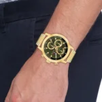 Gold-tone chronograph wristwatch with a black dial and multiple subdials on a man's wrist with a metal bracelet.