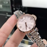 Rose gold and silver Emporio Armani wristwatch with a pink dial, Roman numerals, and crystal markers held against a two-tone metal bracelet.