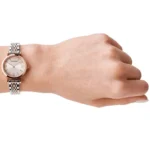 Wrist wearing a two-tone metal wristwatch (rose gold and silver) on a light-skinned arm, shown in profile with the hand relaxed.