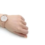 ar11223-emporio-armani-watch-women-pink-dial-stainless-steel-metal-silver-rose-gold-strap-quartz-battery-analog-gianni-t-bar_90 Rose gold wristwatch on a person's left wrist against a white background.