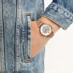 ar11223-emporio-armani-watch-women-pink-dial-stainless-steel-metal-silver-rose-gold-strap-quartz-battery-analog-gianni-t-bar_93 Rose-gold wristwatch with a crystal-studded dial on a denim-clad wrist.