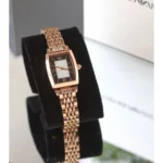 Rose gold-tone women's wristwatch with a rectangular black dial and a diamond-studded center, displayed on a black stand.
