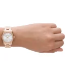 Rose-gold metal wristwatch with a white dial and crystal-studded bezel worn on a person's wrist