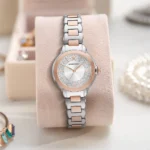 ar11643-emporio-armani-watch-women-crystals-silver-dial-metal-stainless-steel-rose-gold-strap-quartz-analog-mia_12 Two-tone silver and rose-gold Emporio Armani wristwatch with diamond-studded dial on a soft pink display cushion.