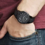 ar1452-emporio-armani-watch-men-black-ceramic-ceramica-hand-11 Black metal chronograph wristwatch on a person’s left wrist, resting over a jeans pocket.