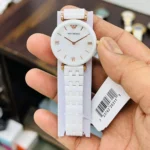 ar1486-emporio-armani-watch-ceramica-women-mother-of-pearl-white-dial-ceramic-strap-quartz-battery-analog-gianni-t-bar_10 White Emporio Armani wristwatch with a white ceramic band and rose-gold hands, held by a hand with a barcode tag nearby.