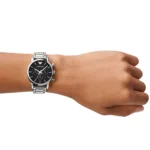 Wrist wearing a silver metal-band watch with a black chronograph dial and white markers.