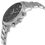 Close-up of a silver stainless steel wristwatch with a black dial and chronograph subdials, showing the crown and bracelet links