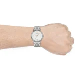 Silver-tone wristwatch with metal link band on a wrist; white dial with Roman numerals and Armani logo