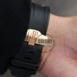 audemars-piguet-royal-oak-offshore-chronograph-26401RO.OO.A002CA.02-balck-dial_2 Close-up of a rose-gold deployment clasp with 'AP' engraving on a black rubber watch strap. wrist visible in background.