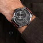 Close-up of a men's chronograph watch with a textured gray dial and multiple subdials on a brown leather strap.