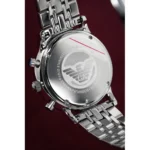 Back view of a silver stainless steel Armani watch with engraved logo and bracelet, set against a dark maroon background