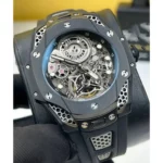 Skeleton mechanical wristwatch with exposed gears and a blue-toned bezel on a black strap