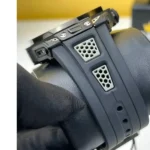 Close-up of a black action camera mount attached to a padded strap, featuring two white honeycomb vents on the housing.
