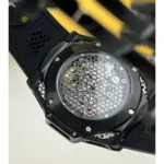 Back of a black sports watch featuring a honeycomb grille and visible pink jewels in the movement