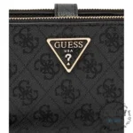 Close-up of a black fabric bag showing a gold Guess triangle logo above a zipper and embossed pattern.