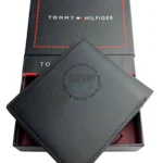 Black leather bi-fold wallet resting on a Tommy Hilfiger gift box.