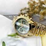 Gold Michael Kors chronograph wristwatch with black dial and linked bracelet resting on a surface
