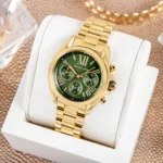 Gold Michael Kors wristwatch with green dial in a white presentation box, gold bracelet visible in close-up