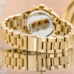Gold-tone Michael Kors watch bracelet with folding clasp, highly polished links and a reflective surface.