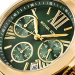 Close-up of a green Michael Kors luxury wristwatch with a gold case, Roman numerals, three subdials, and a date window.
