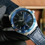 Omega Constellation wristwatch with blue bezel, black dial, and blue leather strap.