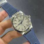 Omega Constellation wristwatch with silver dial, blue Roman numeral bezel, stainless steel case, blue strap, and date window at 6 o'clock.