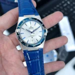 Omega Constellation wristwatch with white dial, blue indices, and blue leather strap.