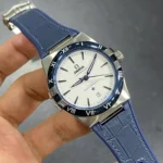 Omega Constellation wristwatch with a white dial, blue bezel, and blue leather strap; date window at 6 o'clock within steel case.