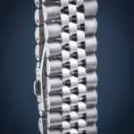 Close-up of a metallic roller chain with shiny cylindrical links connected by hinges, shown vertically against a dark background.