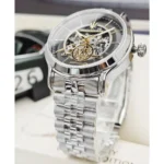 Silver skeleton watch with exposed gears and Maserati trident logo on a black dial with a polished metal link bracelet