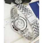 Stainless steel wristwatch with a transparent case back, revealing the mechanical movement inside the watch.