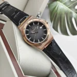 r8851153001-original-maserati-watch-men-black-dial-leather-strap_14 Rose gold wristwatch with a black textured dial and black crocodile-embossed strap resting on a display cushion.