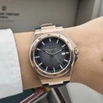 r8851153001-original-maserati-watch-men-black-dial-leather-strap_17 Rose-gold wristwatch with a textured black dial and date window on a light shirt cuff.