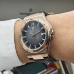 r8851153001-original-maserati-watch-men-black-dial-leather-strap_18 Rose gold wristwatch with a blue textured dial and metal bracelet, showing date at 3 o'clock on the wearer's wrist