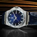 Stainless steel wristwatch with a blue textured dial, silver hour markers, and a blue leather strap; date window at 3 o'clock.