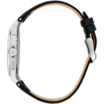 Side view of a silver wristwatch with a black leather strap and a knurled crown with a brand emblem on the crown edge behind the strap buckle area ( leather lining visible).