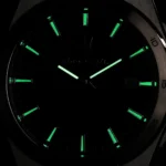 Analog wristwatch with glowing green hour markers and hands in a dark setting