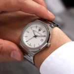 r8853142005-maserati-watch-men-silver-dial-metal-stainless-steel-strap-quartz-battery-analog-three-hand-100m-330ft-stile_5 Silver Maserati wristwatch with a textured white dial and date window on a metal bracelet being worn on a wrist.