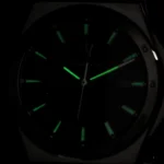 Analog wristwatch in darkness with green luminescent hour markers and hands.