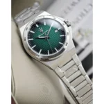 Stainless steel analog wristwatch with a green textured dial, silver hour markers, and a date window at 3 o'clock.