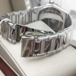 Close-up of a silver metal watch bracelet with a deployment clasp on a white surface.