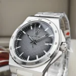 Stainless steel wristwatch with a dark, textured grid dial, silver markers, and a date window at 3 o'clock.